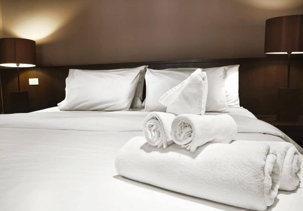 Impeccably Made Bed with Crisp Towels, Exemplifying Hotel Cleaning Standards
