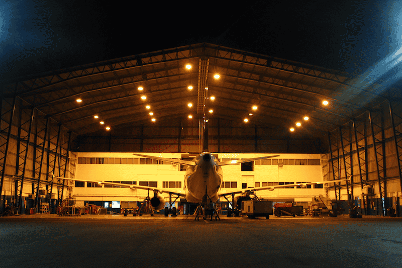An airline hangar illuminated at night, highlighting the need for meticulous airport cleaning services to maintain a clean and organized environment.