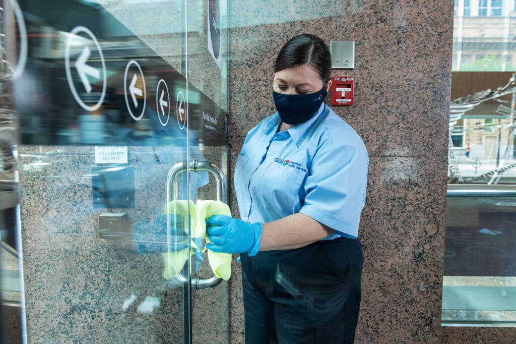 Commercial Cleaning Services - GDI Employee Cleaning Glass Lobby Door Handle
