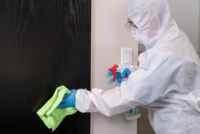 Professional in Hazmat Suit Performing Disinfection Services on Door with Microfiber Cloth and Disinfectant